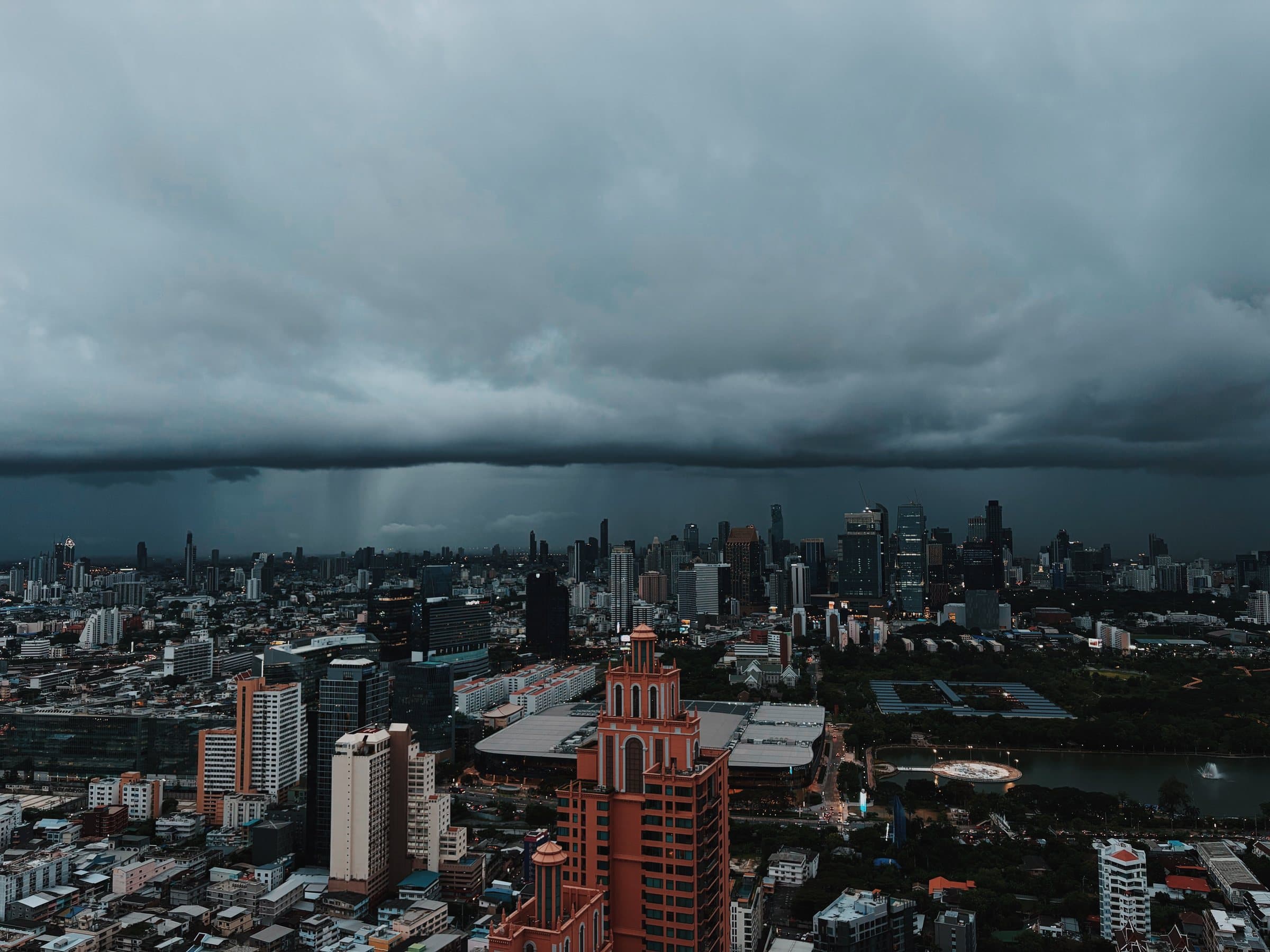 A storm front over the Bangkok skyline, with rain falling beyond the business district.