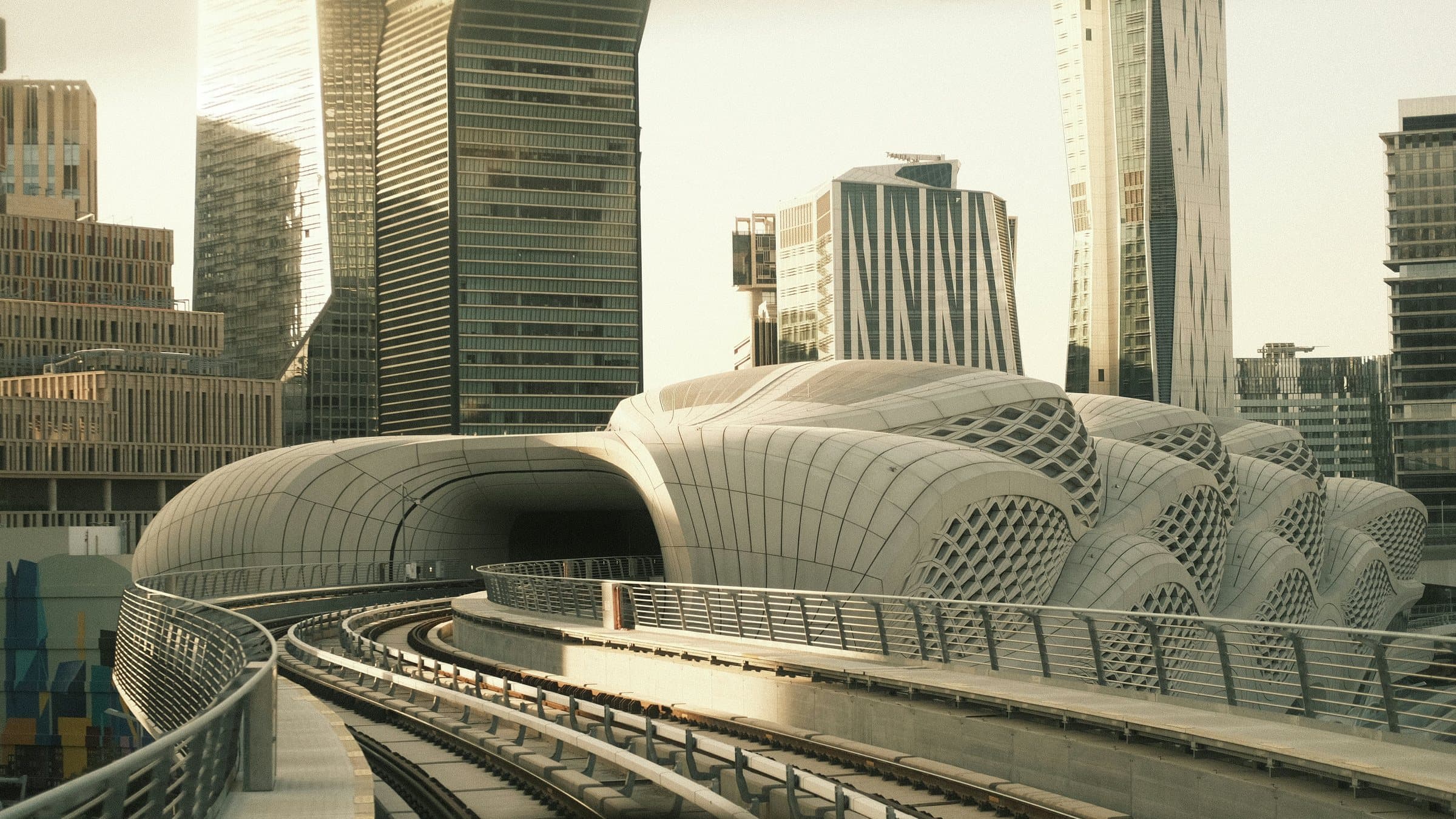 An elevated metro line curving into the KAFD station in Riyadh, with office towers behind.