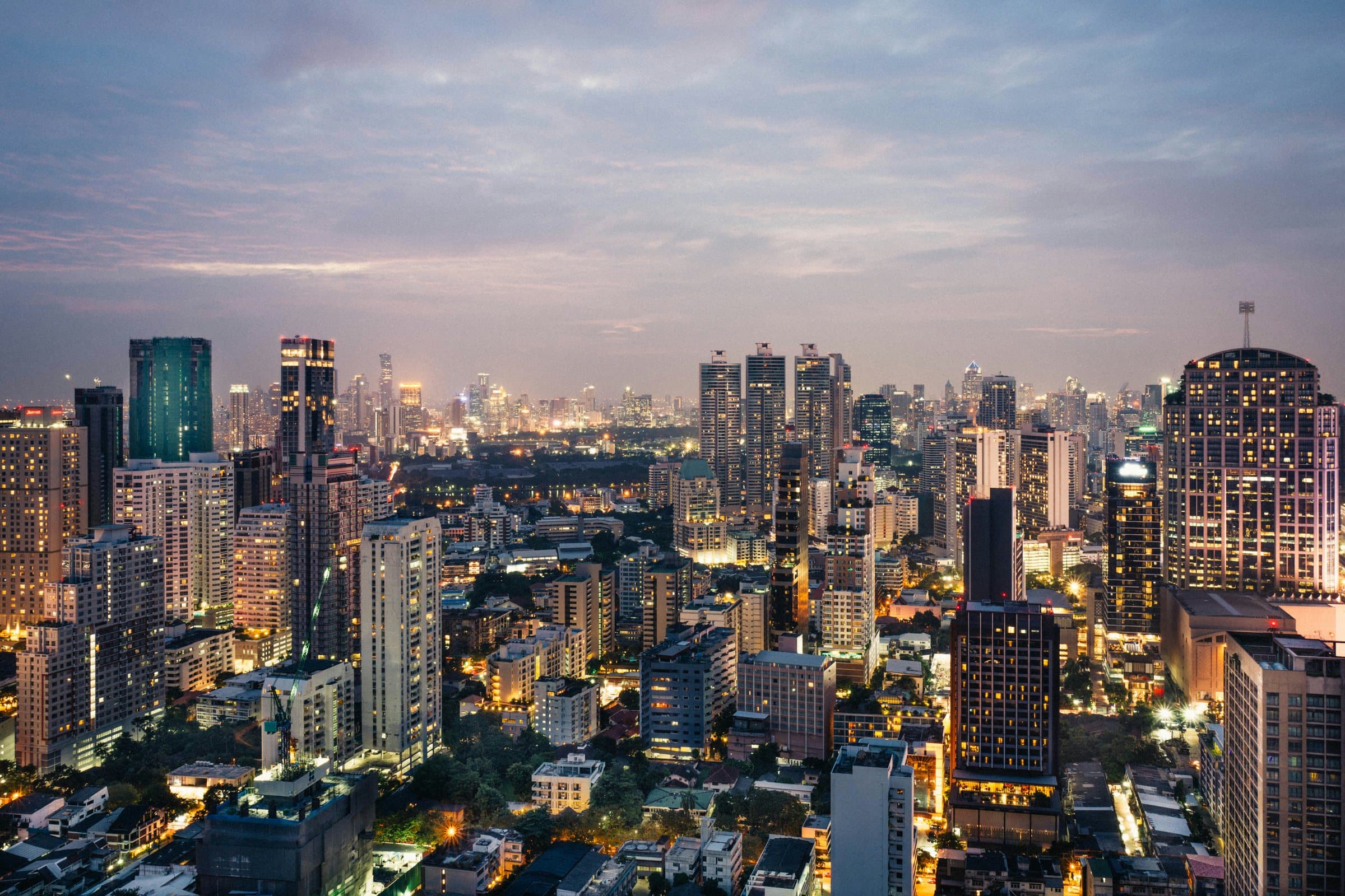 The Bangkok skyline at dusk, with lit towers across the city centre.
